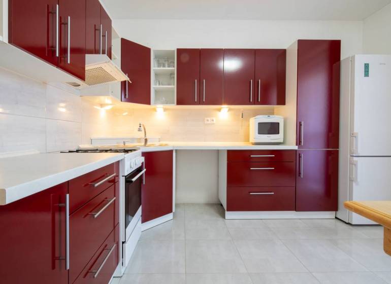 Znížená cena za 4 izbový rodinný dom v obci Jahodná - Kuchyňa v rodinnom dome s červenými skrinkami a bielymi spotrebičmi.