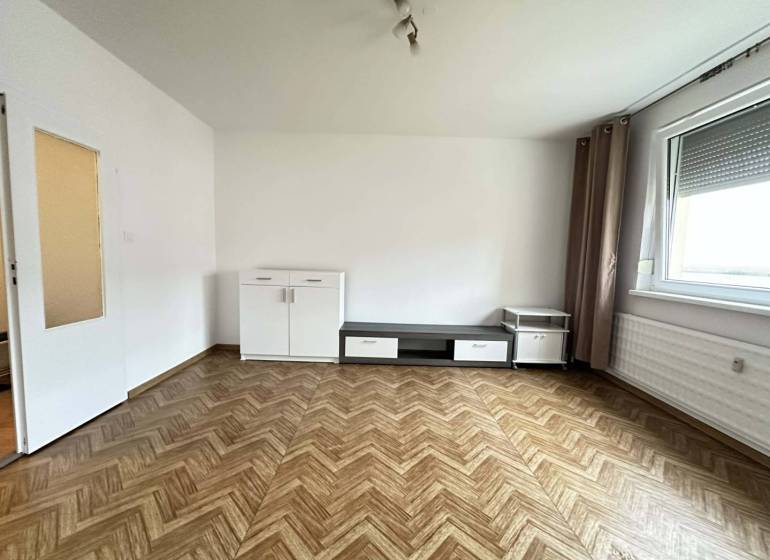 ☎️  0918/197 701  Na prenájom 1 izbový byt s balkónom a pivnicou v mes - Izba s podlahou s dreveným dekorom, bielym nábytkom a veľkým oknom v 1-izbovom byte.