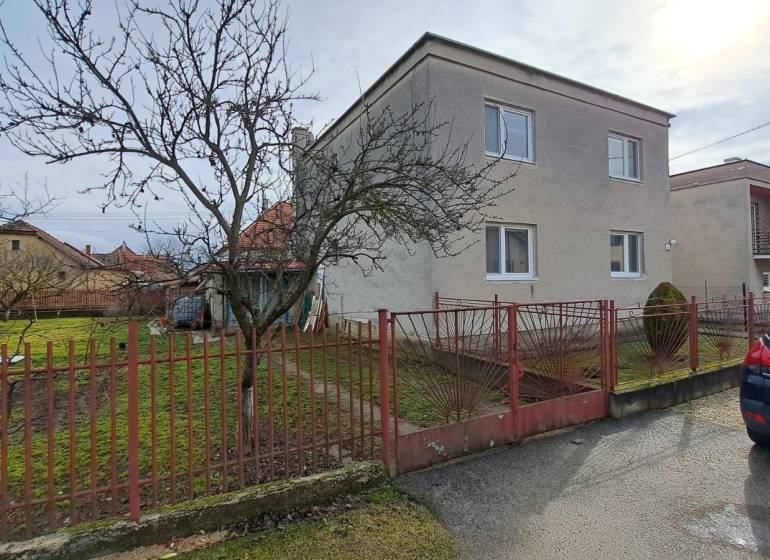 NA PREDAJ 6 izbový rodinný dom v obci Hrušovany  - Rodinný dom v Hrušovanoch s upravenou záhradou, skleníkom a kovovým plotom.