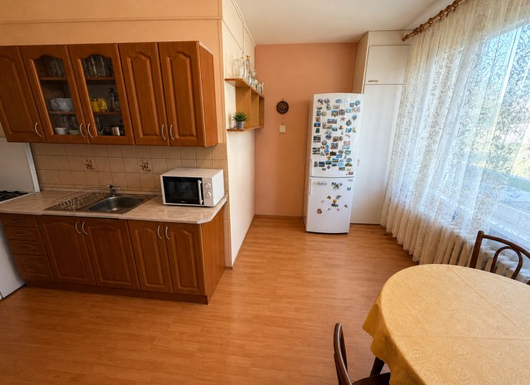  3 izbový byt s balkónom 75m2 Zvolen - Západ - Kuchyňa v 3-izbovom byte s podlahou s dreveným dekorom a jedálenským kútom.