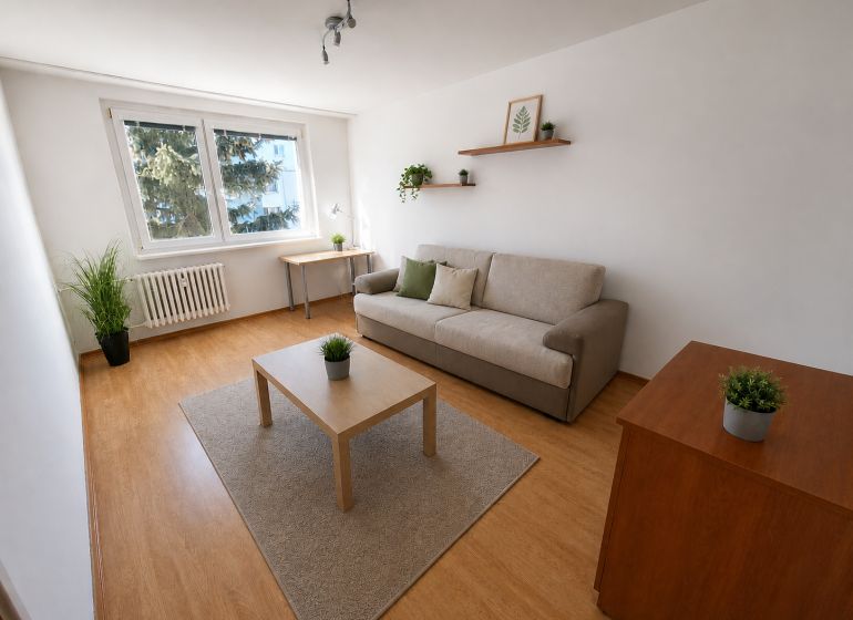 2-izbový byt, 51 m², samostatné izby, tichý, výhľad do zelene,K.Adlera - Obývacia izba v 2-izbovom byte s podlahou s dreveným dekorom a rozkladacou pohovkou.