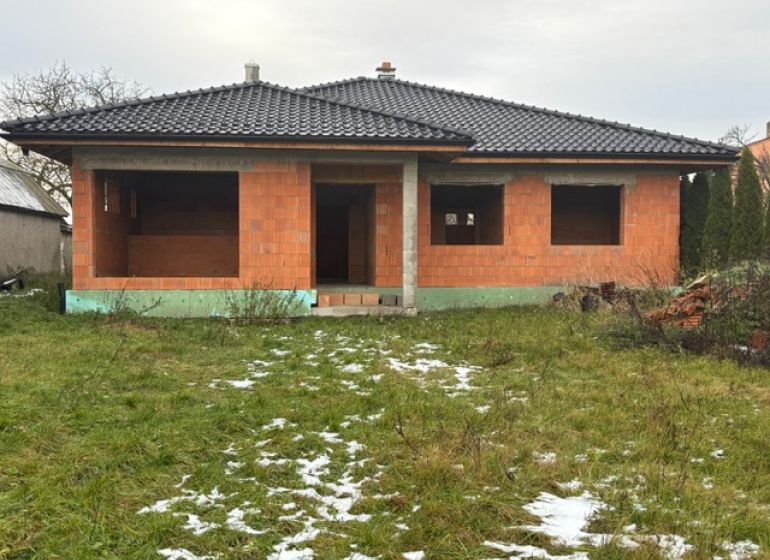 NOVOSTAVBA  - Rozostavaný bungalov v obci Dúbravka - Nedokončený rodinný dom v Dúbravke, s čiernou strechou a prázdnymi oknami, v zimnej záhrade.