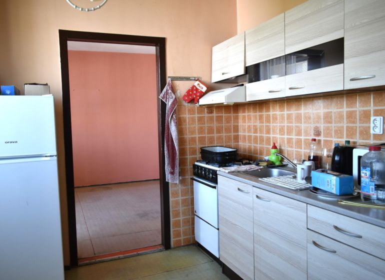  REZERVOVANÉ 3-izbový byt s balkónom na sídlisku Juh - Kuchyňa v 3-izbovom byte s dlaždicovým obkladom a podlahou s dreveným dekorom.
