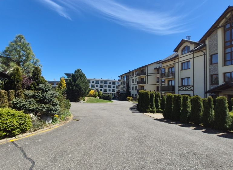 Investičný apartmán Vysoké Tatry - Stará Lesná s balkónom a park.miest - Zeleň v okolí rekreačných apartmánov na Starej Lesnej vo Vysokých Tatrách pod modrou oblohou.