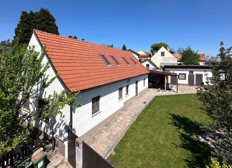 3-izbový dom s nádherným výhľadom a historickou vínnou pivnicou, Berg - Rodinný dom v meste Berg s červenou strechou a zeleným trávnikom.