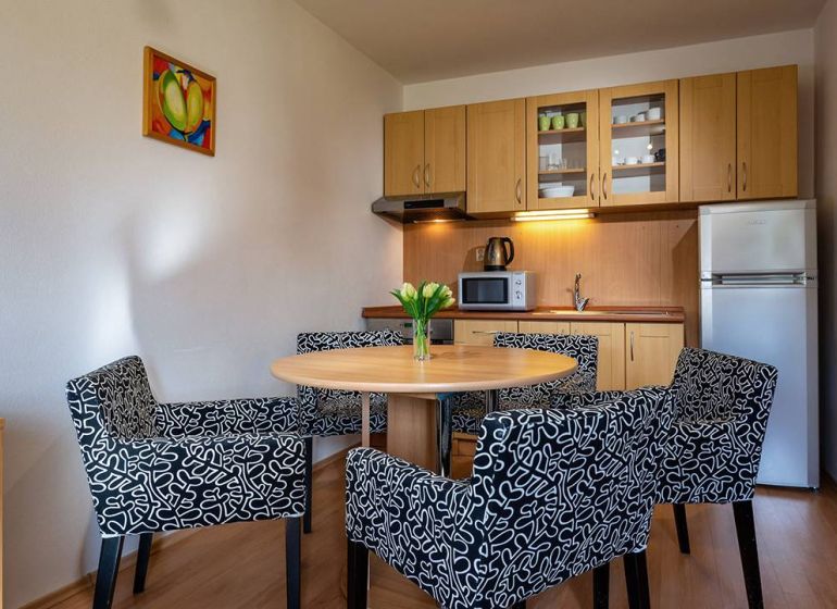 Príjemný rekreačný apartmán priamo pod zjazdovkou v Telgárte - Kuchynský kút s jedálenským stolom a kreslami v Rekreačnom apartmáne, podlaha s dreveným dekorom.