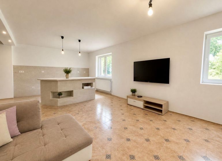 Dvojpodlažný rodinný dom, Bytča - Kolárovice - Obývacia izba v rodinnom dome s TV, pohovkou a dlažbou.