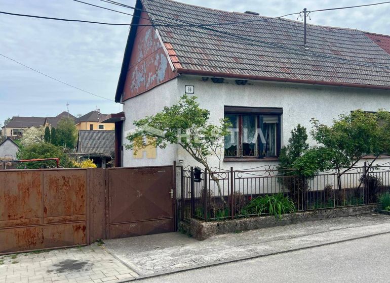 NOVINKA NA TRHU | Rodinný dom v obci Cerová – ideálne miesto pre pokoj - Rodinný dom v Cerovej s bránou a malou záhradou, obkolesený zeleňou.