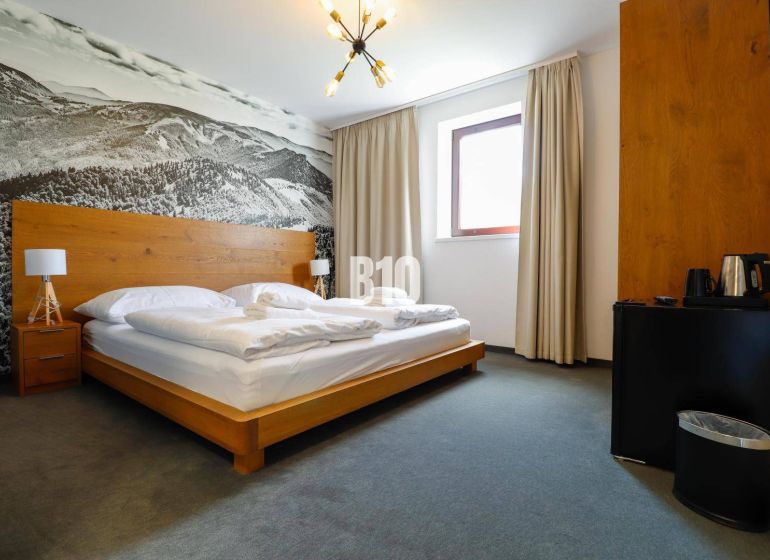VKUSNE ZARIADENÝ apartmán v TOP lokalite v lyž. stredisku SNOWLAND Val - Spálňa v rekreačnom apartmáne s drevenou posteľou a veľkoformátovou fotografiou krajiny.