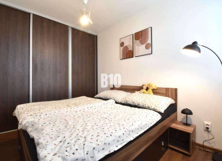 3-izbový byt s parkovaním vo dvore - Spálňa v 3-izbovom byte so vstavanou skriňou a posteľou s dreveným dekorom.
