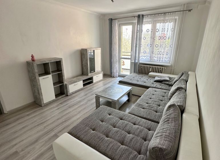 Prenájom moderný 2,5 izbový byt, Šalviová ulica, Bratislava II.Ružinov - Obývačka v 3-izbovom byte s podlahou s dreveným dekorom, veľkou sedačkou a televíziou.