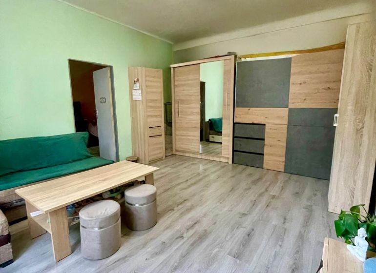 EXKLUZÍVNY PREDAJ - 2-izbový byt byt s predzáhradkou v srdci Nitry - Obývacia izba s podlahou s dreveným dekorom, sedačkou a skrinkami v 2-izbovom byte.