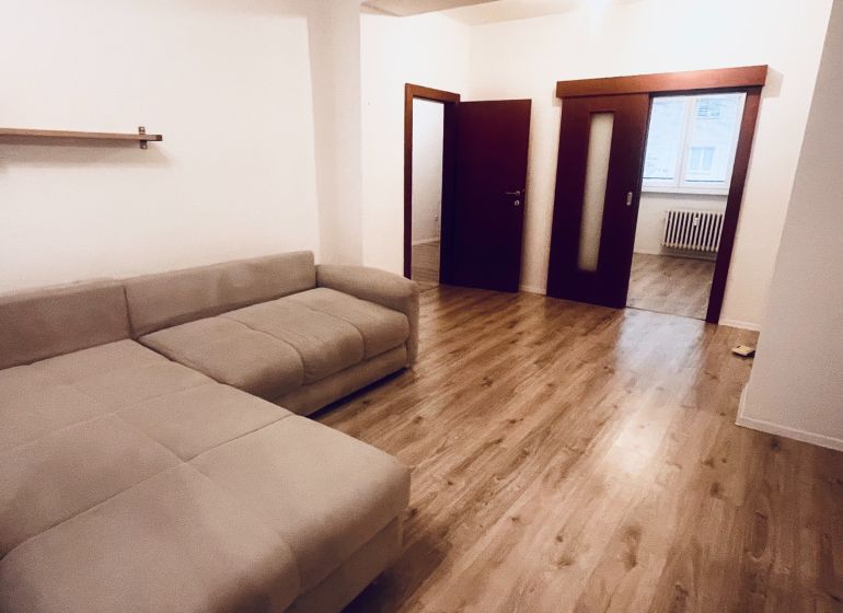 PREDAJ: 3i s balk. 67 m2; Uhlisko-Banská Bystrica; 205.000 € - Obývacia izba s pohodlnou sedačkou a podlahou s dreveným dekorom v 3-izbovom byte.