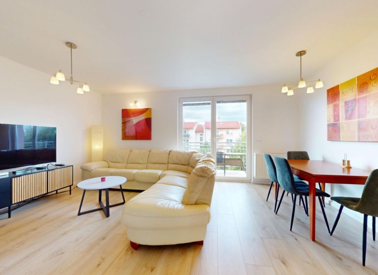 | Pekný a priestranný 3-izbový byt | 70m² |  - Obývačka v 3-izbovom byte s podlahou s dreveným dekorom, sedačkou a jedálenským stolom.