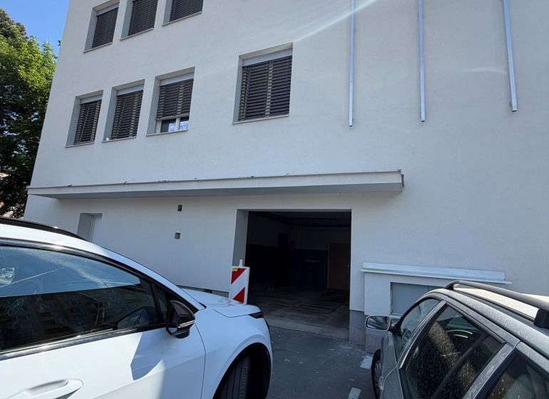 Ponúkame na prenájom 2 garáž / priestor v blízkosti centra Prievidze - Budova s garážami na dlhej ulici 3 v Prievidzi, zaparkované autá pred budovou.