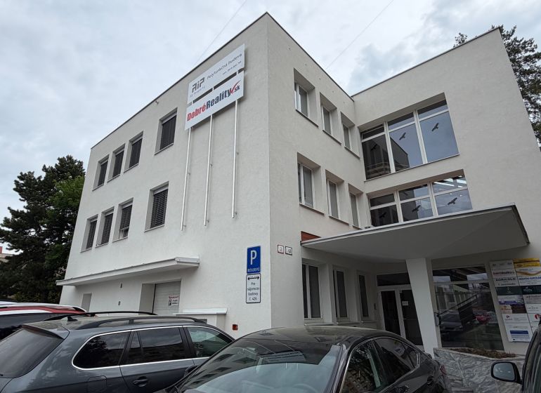 Ponúkame najlacnejšie  kancelárske priestory v Prievidzi  - Budova kancelárií na Dlhej ulici v Prievidzi so zaparkovanými autami.