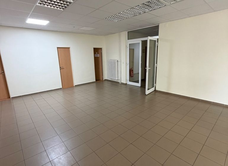 Ponúkame na prenájom priestrannú kanceláriu vPrievidzi - Prázdne kancelárie s dlaždicovou podlahou a bielymi stenami.