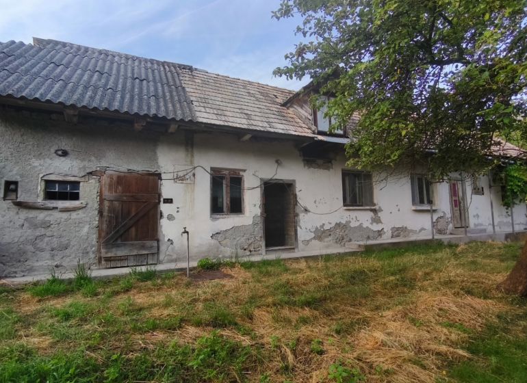 Kamenný vidiecky dom v obci Čelovce okres Veľký Krtíš. - Rodinný dom v Čelovciach s opotrebovanou omietkou, drevenými dverami a záhradou.