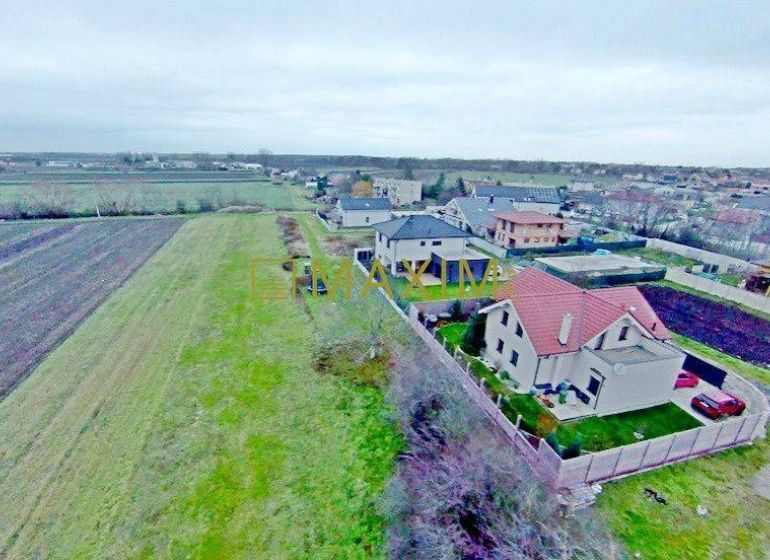 PREDAJ - Stavebný pozemok v meste Stupava - Pohľad na pozemky - bývanie v Stupave s rozmanitým terénom a susednými domami.