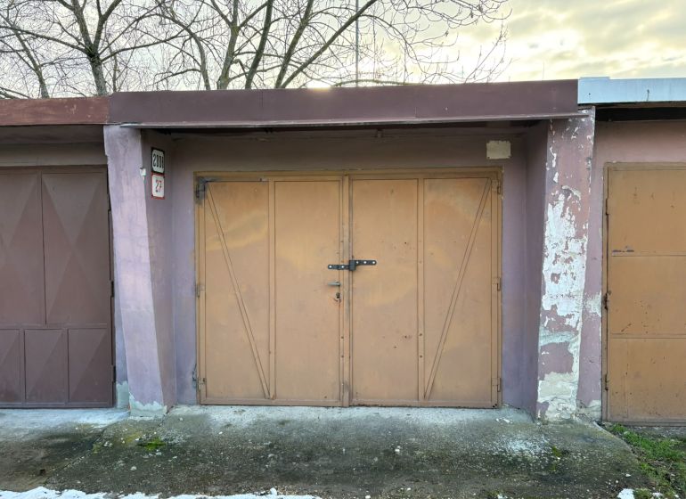 PREDAJ – Garáž na predaj v meste Galanta za kaštieľom  - Garáže v Galante s kovovými dverami a opotrebovanými fasádami, obklopené stromami.