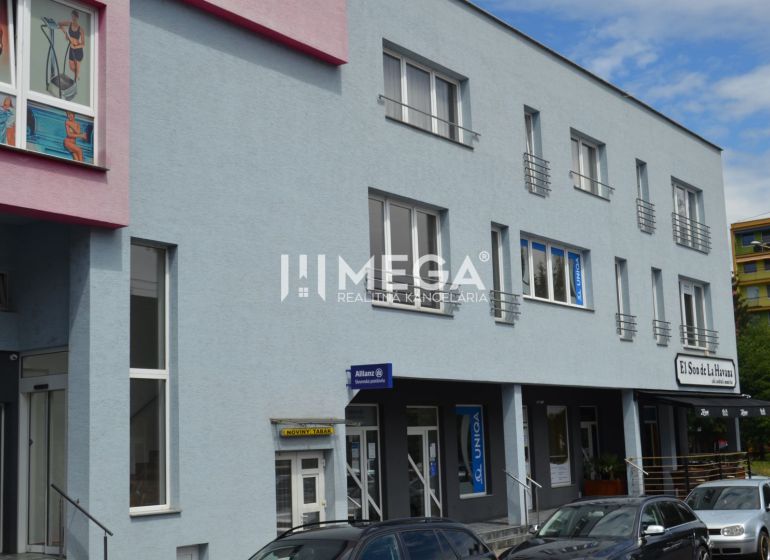 PRENÁJOM obchodného priestoru v centre Humenného (74 m2) - Obchodné priestory na ulici Osloboditeľov v Humennom s farebnou fasádou a autami v popredí.