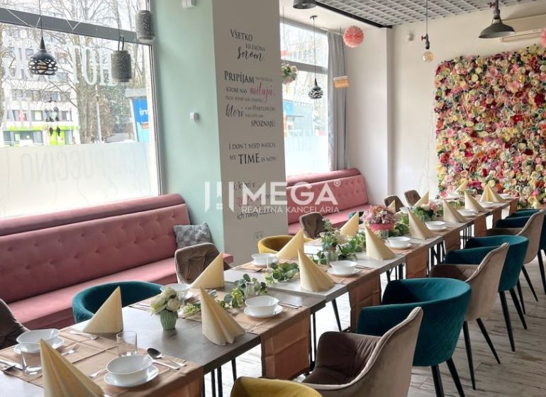 ODSTÚPENIE ZABEHNUTEJ REŠTAURÁCIE Bistro Dominika–VRANOV N/T - Gastro priestory s dekorovaným stolom, kvetinovou stenou a podlahou s dreveným dekorom.