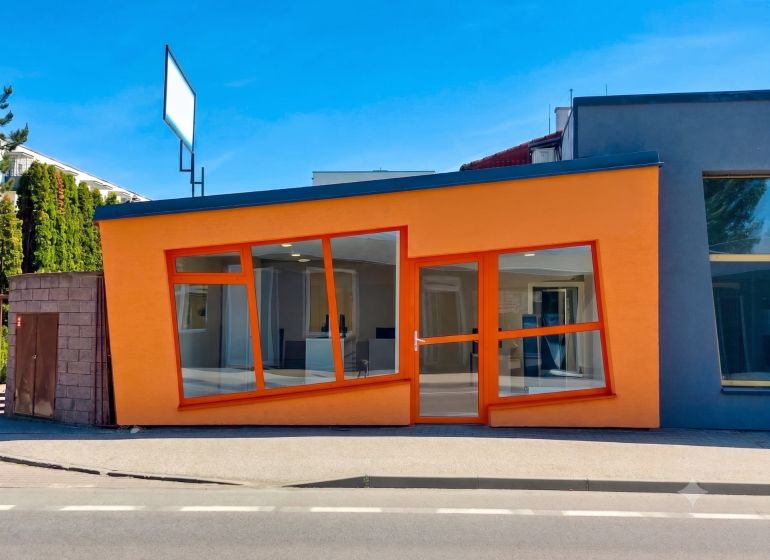 Obchodný priestor 75m2 | Zlatovská, Trenčín - Oranžová fasáda obchodných priestorov na Zlatovskej ulici v Trenčíne s veľkými sklenenými oknami.