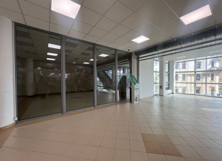 Obchodný priestor na prenájom 79 m² - Banská Bystrica NO718ZL - Presklené obchodné priestory s dlažbou a bankomatom, interiér s veľkými oknami.