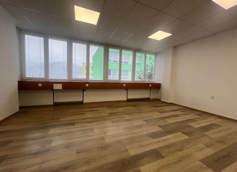 Prenájom kancelárske priestory 27 m² -Banská Bystrica, Zvolenská cesta - Prázdna kancelária s podlahou s dreveným dekorom a veľkými oknami.