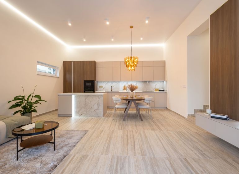 MODERNÝ 4-IZBOVÝ BUNGALOV | ZEMPLÍNSKA ŠIROKÁ - Kuchyňa a obývačka v rodinnom dome s dekoratívnym svietidlom a podlahou s dreveným dekorom.