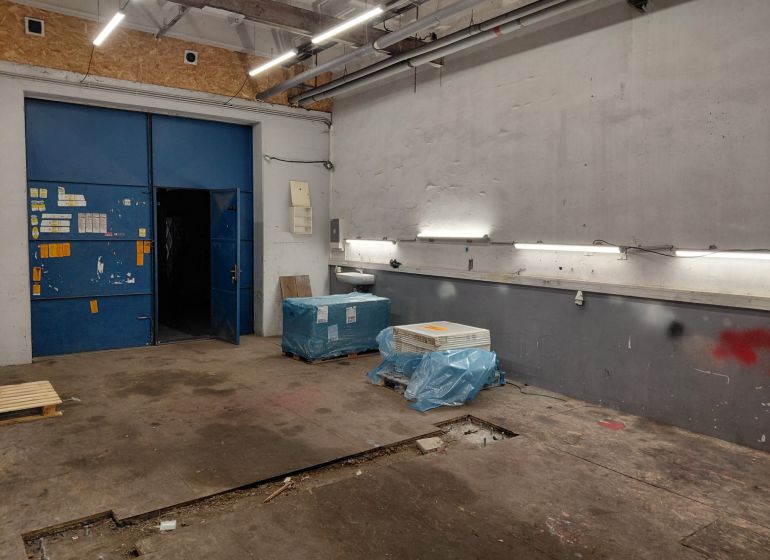 Prenájom skladu 55 m2 na Tomášikovej ul. v Ružinove - Sklady a haly s modrými dverami, osvetlením a materiálmi na podlahe s dreveným dekorom.