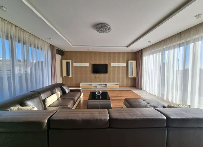 PRENÁJOM- Jedinečný, luxusný byt 148 m2 s terasami a parkovaním -Nitra - Obývačka 4-izbového bytu s koženou sedačkou a televízorom na ulici Dolnohorská.