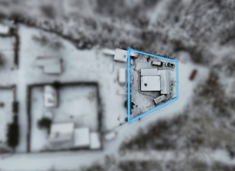 Rekreačná chata pri Váhu - Dlhá nad Váhom - bez rezervačnej zálohy - Letecký pohľad na zasneženú chatu v obci Dlhá nad Váhom, zvýraznenú modrou čiarou.
