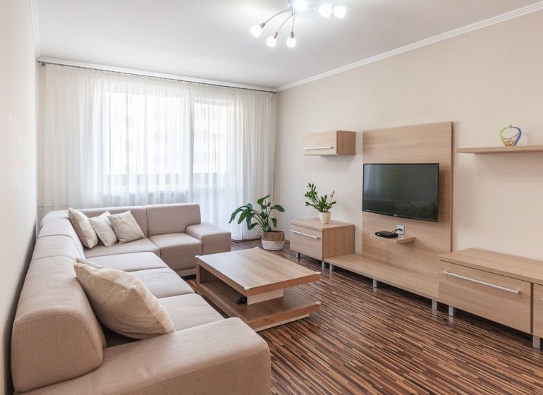 Predaj 3i bytu 84m2 - dva balkóny , Nábrežná v NZ - Obývacia izba v 3-izbovom byte s pohovkou, televízorom a podlahou s dreveným dekorom.