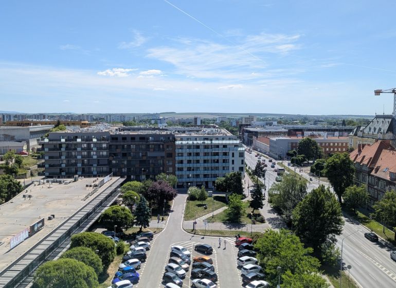 3 izbový byt v centre mesta na Štúrovej ulici s krásnym výhľadom - Pohľad na Štúrovu ulicu v Nitre s bytovými domami a parkoviskom.