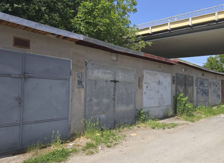 NA PREDAJ MUROVANÁ GARÁŽ 18 m² VO ZVOLENE – ELEKTRINA, VLASTNÝ POZEMOK - Garáže na Jesenského ulici v Zvolene popri ceste so zeleňou a grafitmi.