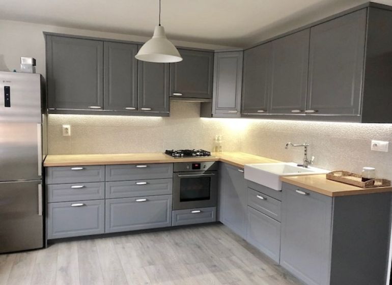 NA PRENÁJOM Pekný 2 izbový byt v Centre Pezinka 700,- EUR - Moderná kuchyňa v 2-izbovom byte so sivými skrinkami a podlahou s dreveným dekorom.