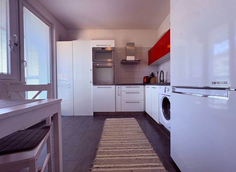 Na predaj: 4 izb.byt + BALKON + PIVNICA - Kuchyňa 4-izbového bytu s bielymi skrinkami a tmavou podlahou s dreveným dekorom.