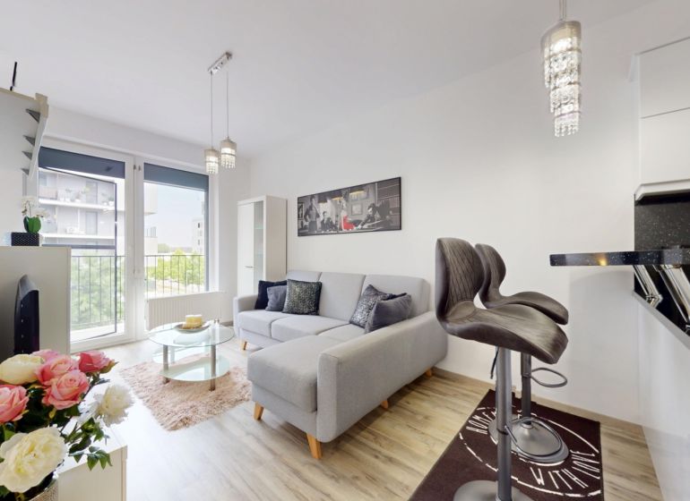 | Zariadený 1,5 izbový byt | 35m² | SLNEČNICE - Svetlý 2-izbový byt s pohovkou, barovými stoličkami a výhľadom cez veľké okno.