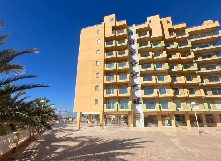 Predaj- Apartmány - La Manga del Mar Menor- Španielsko  - Rekreačný apartmán v La Manga del Mar Menor s palmami a jasnou oblohou.