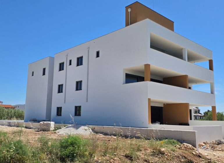 CHORVÁTSKO - Apartmány 60 m od mora - PRIVLAKA - Biely bytový dom s balkónmi v Privlake oproti modrej oblohe, 3-izbový byt.