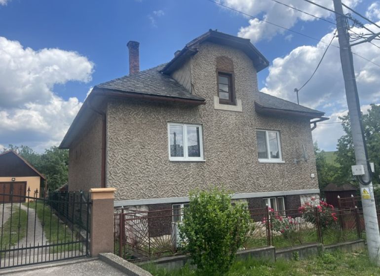 Rodinný dom zo záhradou - Rudná - Rodinný dom v Rudnej s dvojpodlažnou fasádou, oploteným pozemkom a modrou oblohou.