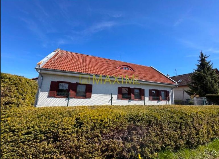 Rodinný dom v obci Kuchyňa - Rodinný dom v Kuchyni s červenou strechou, obklopený živým plotom.