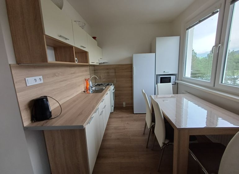 Krásny 3 izbový byt na prenájom. - Kuchyňa v 3-izbovom byte s podlahou s dreveným dekorom a moderným zariadením.