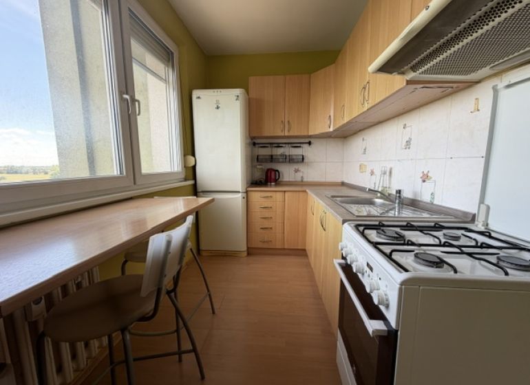 Predaj pekný 1 izbový byt, 35 m2, Dudvážska ulica, BA II. - Kuchyňa v 1-izbovom byte s podlahou s dreveným dekorom a svetlým nábytkom.