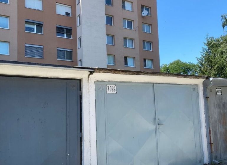 PREDAJ - Garáž v Stupave na ulici Železničná - Garáže na Železničnej ulici v Stupave, s bytovým domom v pozadí.