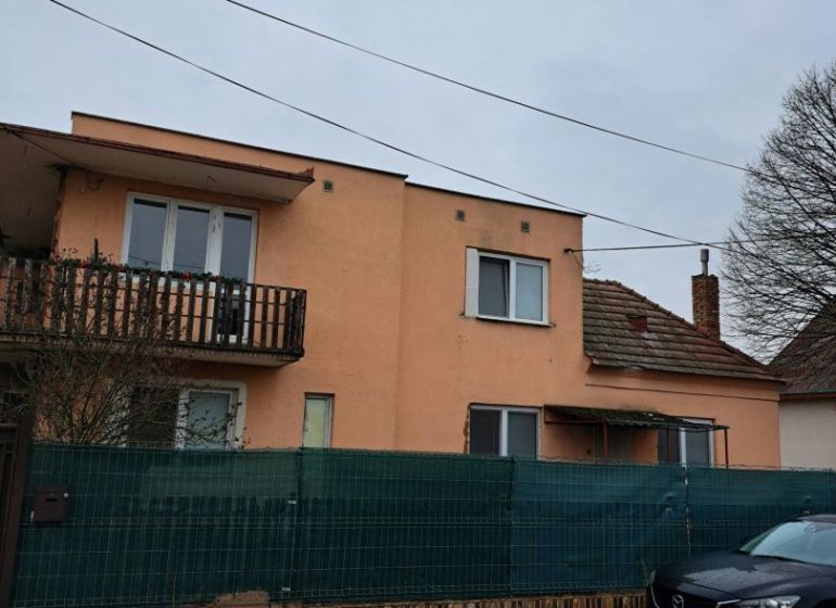 Dom na bývanie a podnikanie na 15 ár. pozemku 35 km od BA - Rodinný dom v Orechovej Potôni s oranžovou fasádou, balkónom a autom pred ním.