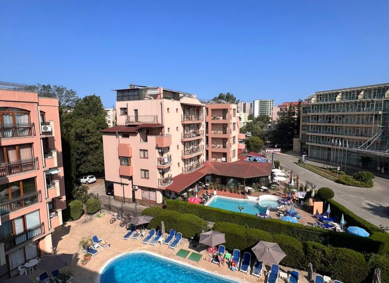 Moderná garsónka (41 m²) s výhľadom na bazén – Rezort ANTARES - Bazénový areál s apartmánovými domami a ležadlami v Slnečnom pobreží.