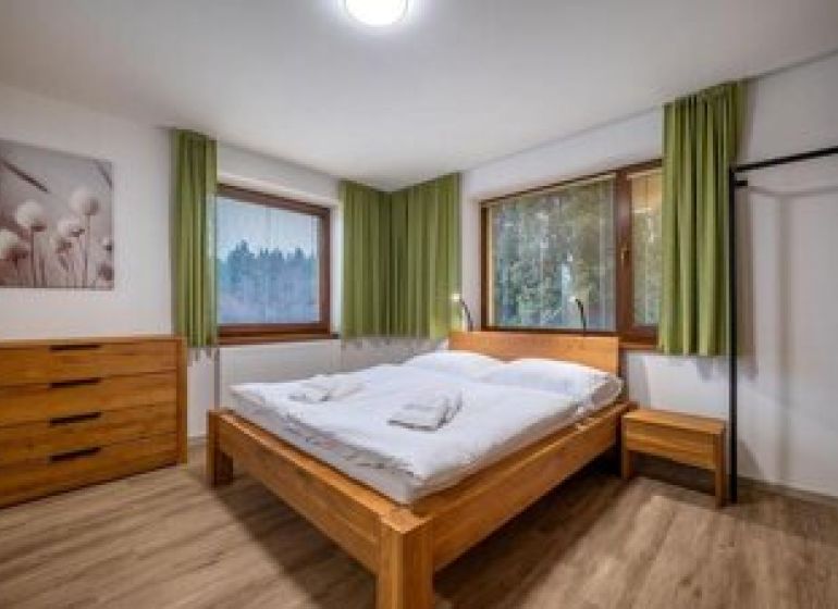 Predaj! Rekreačný apartmán pod Tatrami – Dovalovo - Spálňa v 1-izbovom byte s dvomi posteľami a podlahou s dreveným dekorom.