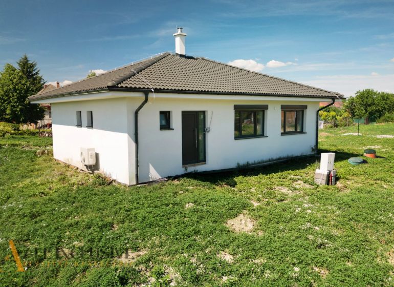 Projekt ČEREŠŇOVÁ ALEJ – 10 rod. domov/pozemk., Jelka - Rodinný dom v Jelke s bielou fasádou a šikmou strechou na zelenej záhrade.